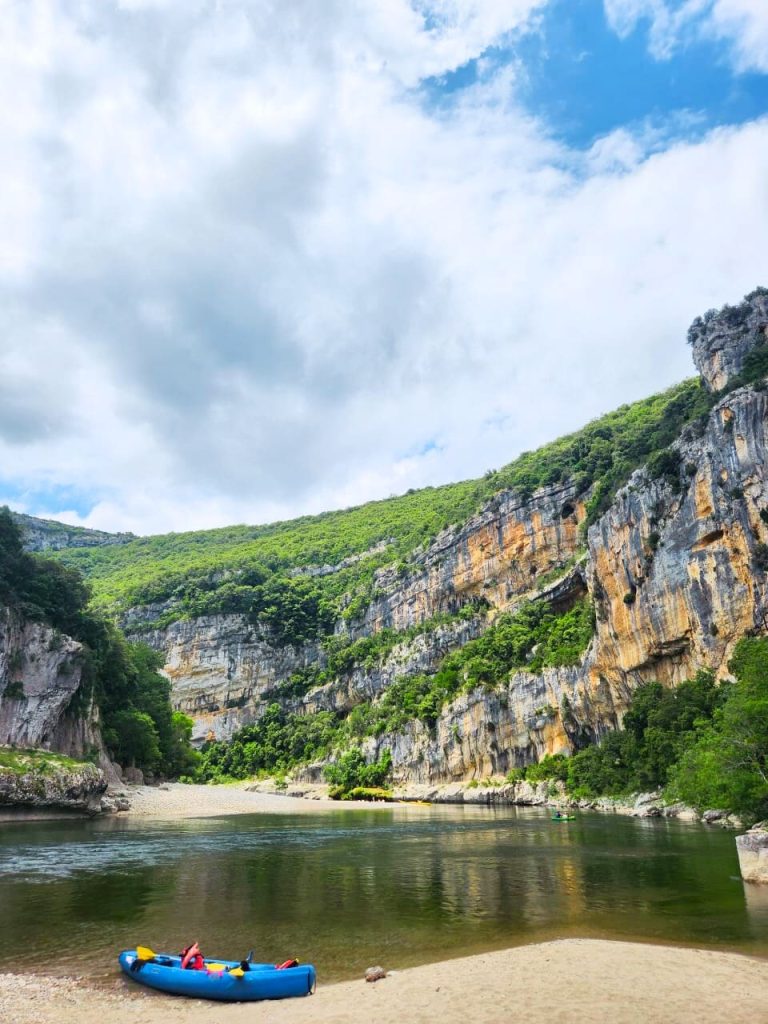 Canoë sur une plage au bord de la rivière dans les Gorges de l’Ardèche, activité nature pour voyageurs incontournable pour les clients de la conciergerie en Sud Ardèche.