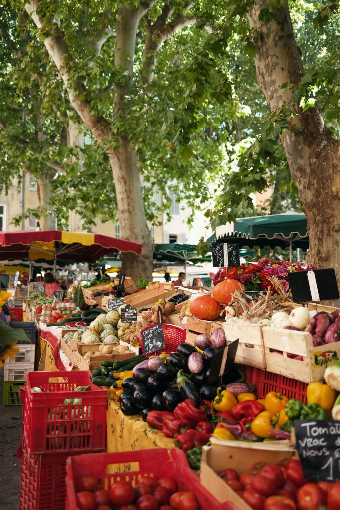 Marché local en Ardèche avec produits frais et artisanaux sous les platanes. Parfait pour les clients de conciergerie vallon pont d'arc et alentours.